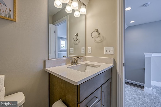 half bath with toilet, vanity, baseboards, and recessed lighting