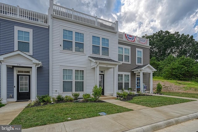view of property featuring a balcony and a front lawn