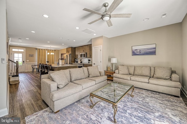 living room with dark wood-type flooring, recessed lighting, ceiling fan, and a chandelier