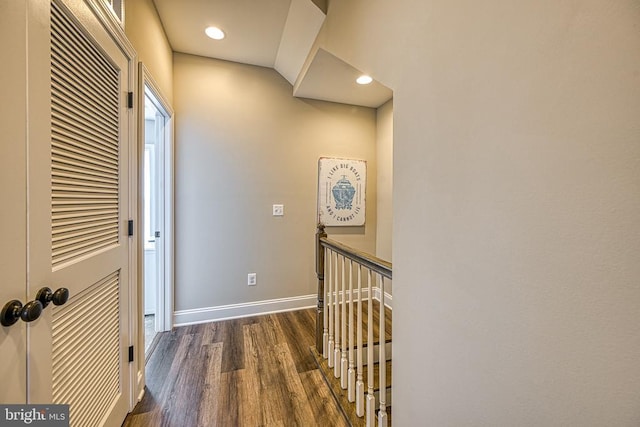 hallway with an upstairs landing, baseboards, wood finished floors, and recessed lighting