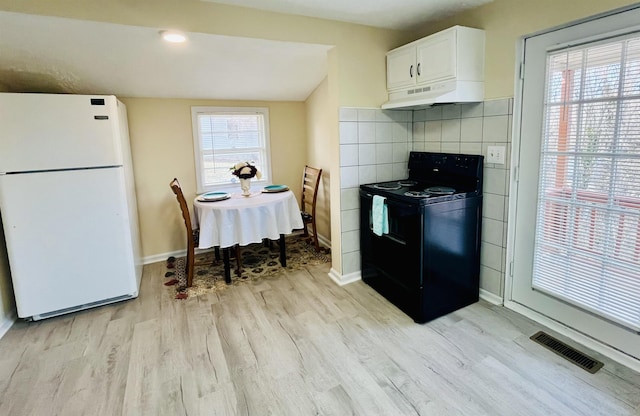 1204 3rd St, Waynesboro, VA 22980 - kitchen with freestanding refrigerator, under cabinet range hood, light wood finished floors, visible vents, and black electric range