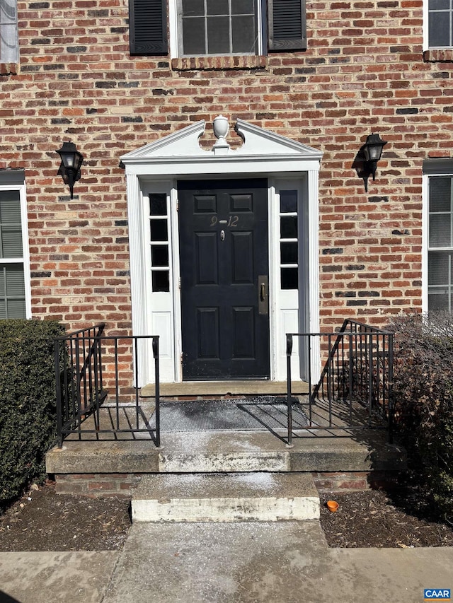 view of exterior entry featuring brick siding