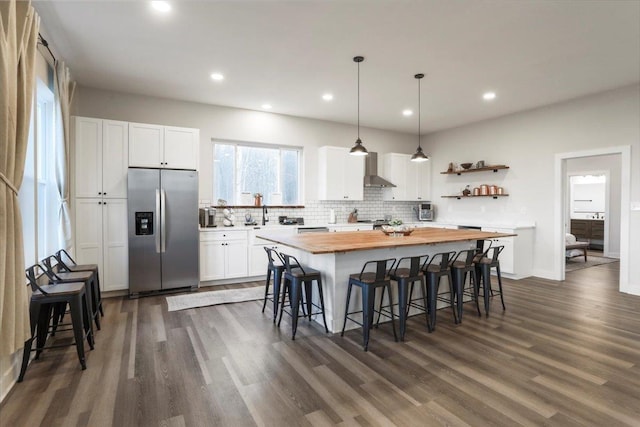 115 Mountain Top Ln, New Market, VA 22844 - kitchen with butcher block countertops, wall chimney range hood, a breakfast bar area, stainless steel fridge, and a center island