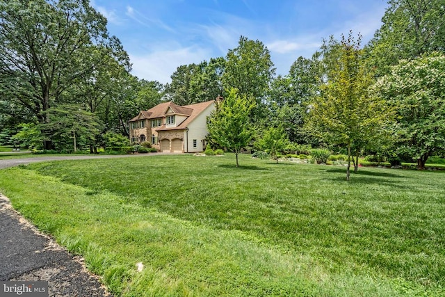 - view of green lawn featuring a garage and asphalt driveway