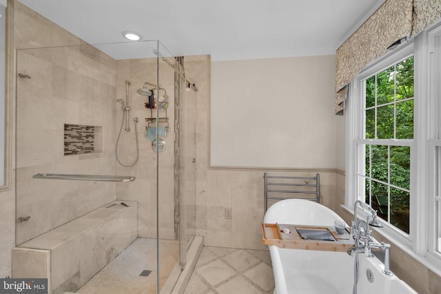  - bathroom with a stall shower, a freestanding tub, tile walls, tile patterned flooring, and wainscoting