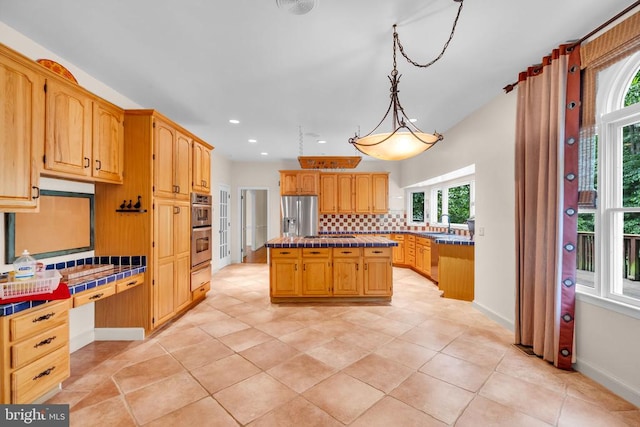  - kitchen featuring stainless steel appliances, tile countertops, decorative backsplash, a center island, and recessed lighting