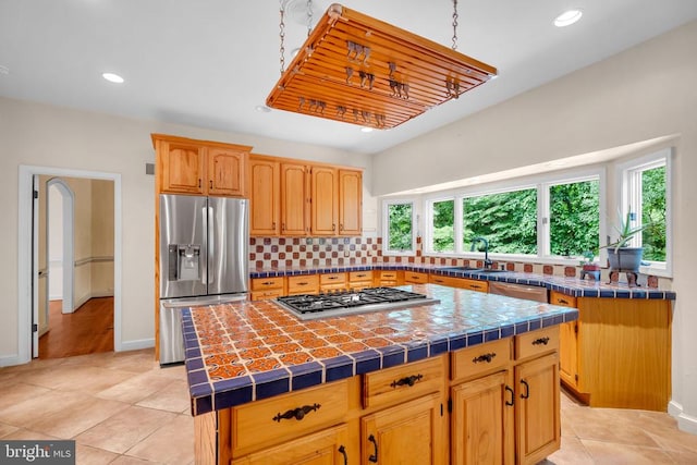  - kitchen with appliances with stainless steel finishes, a kitchen island, tile countertops, plenty of natural light, and recessed lighting