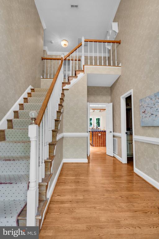 - stairway with wallpapered walls, wood finished floors, and a high ceiling