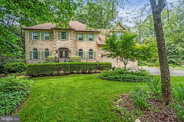  - colonial house with a front lawn, asphalt driveway, brick siding, french doors, and a garage