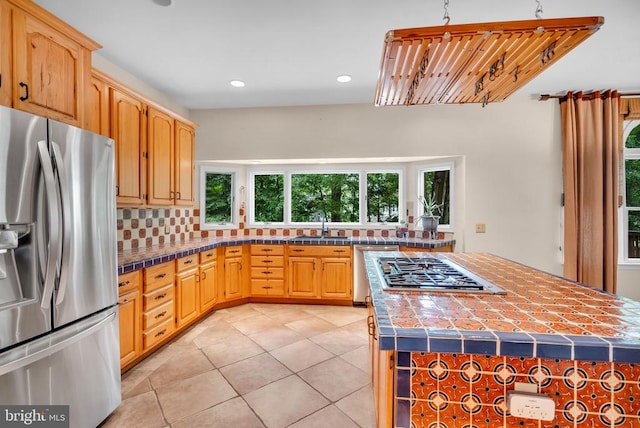  - kitchen with stainless steel appliances, decorative backsplash, light tile patterned floors, recessed lighting, and a center island