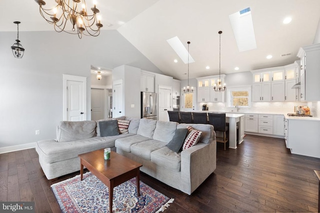  - living room featuring a chandelier, high vaulted ceiling, dark wood-style floors, and a skylight