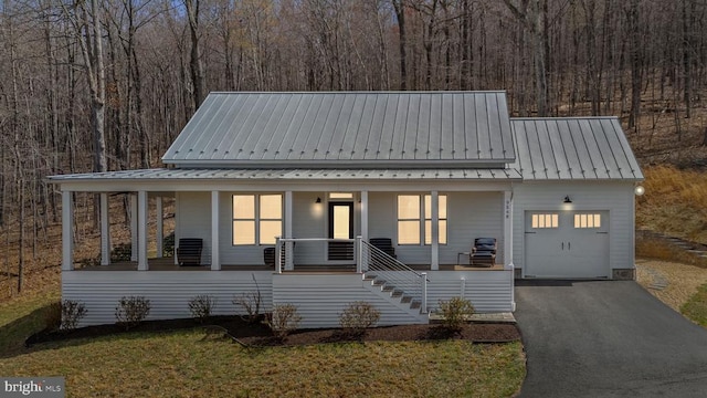  - view of front of property featuring a porch, a metal roof, asphalt driveway, stairway, and a garage