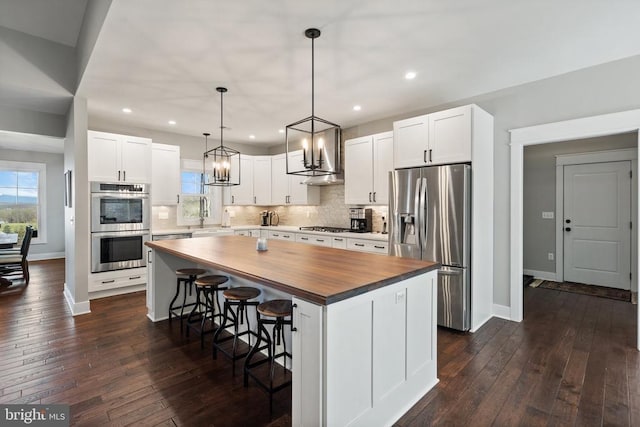 - kitchen with wooden counters, stainless steel appliances, a center island, tasteful backsplash, and dark wood-type flooring