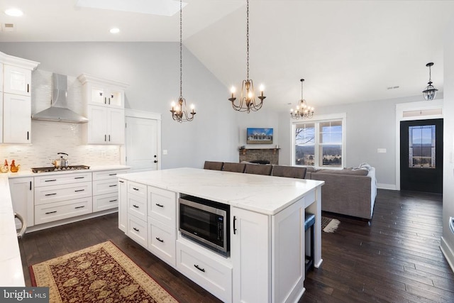  - kitchen with wall chimney exhaust hood, stainless steel appliances, a chandelier, dark wood-style floors, and backsplash