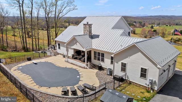 - rear view of house with a chimney, a fenced backyard, a standing seam roof, and a metal roof