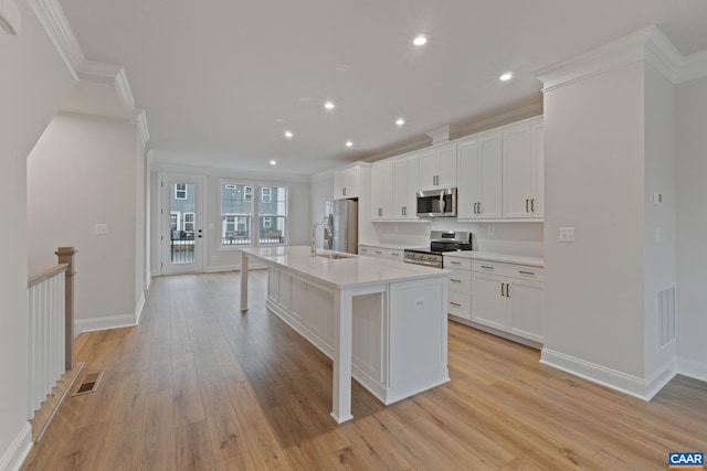 27 Woodburn Rd, Charlottesville, VA 22901 - kitchen with appliances with stainless steel finishes, ornamental molding, an island with sink, light wood-style flooring, and light countertops