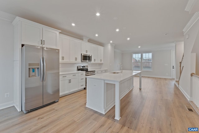 27 Woodburn Rd, Charlottesville, VA 22901 - kitchen with stainless steel appliances, crown molding, an island with sink, light wood-style floors, and white cabinets