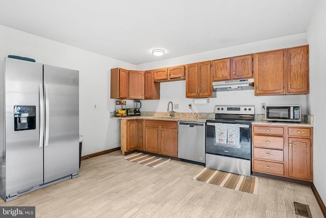 5129 Pecan Dr, Fredericksburg, VA 22407 - kitchen featuring stainless steel appliances, under cabinet range hood, a sink, light wood-type flooring, and brown cabinets
