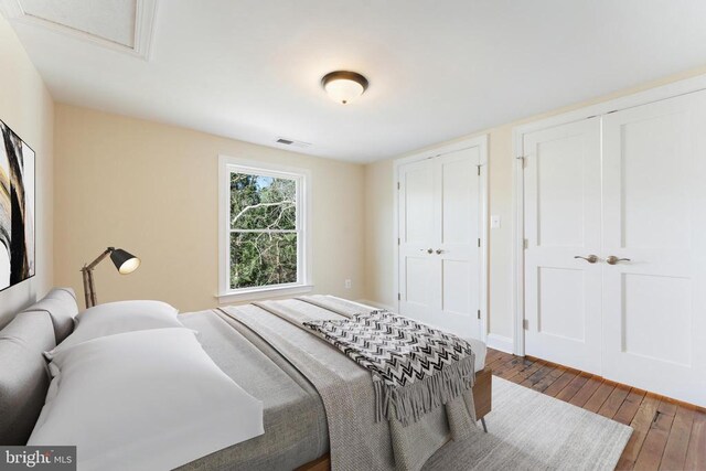 bedroom with two closets and dark wood-type flooring