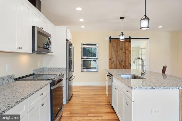 kitchen with stainless steel appliances, sink, a center island with sink, and white cabinets