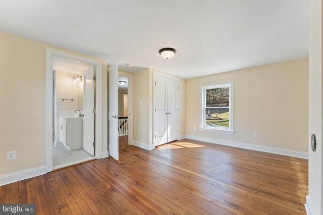 unfurnished bedroom with sink and hardwood / wood-style floors