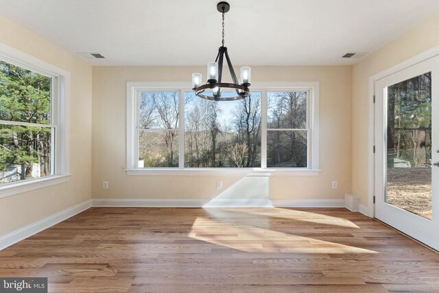 unfurnished dining area featuring hardwood / wood-style floors, plenty of natural light, and a chandelier