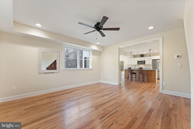 unfurnished living room with light hardwood / wood-style flooring and ceiling fan