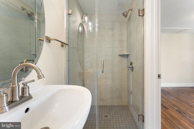 bathroom featuring wood-type flooring, an enclosed shower, and sink