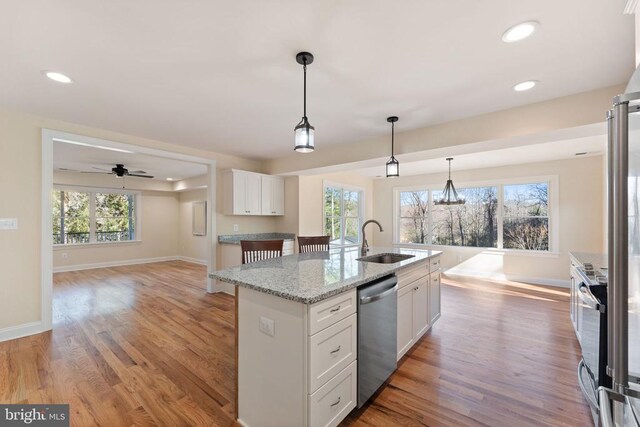 kitchen featuring sink, white cabinets, a kitchen island with sink, light stone counters, and stainless steel appliances