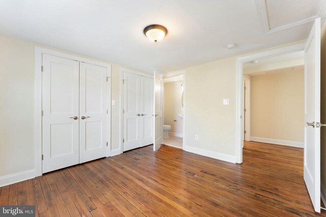 unfurnished bedroom with dark hardwood / wood-style flooring and two closets