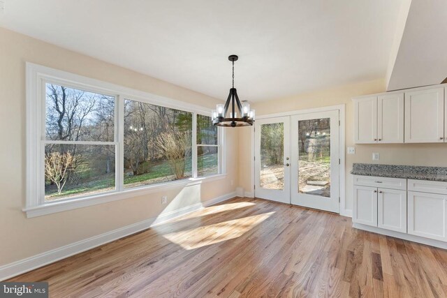 unfurnished dining area featuring a chandelier and light hardwood / wood-style floors