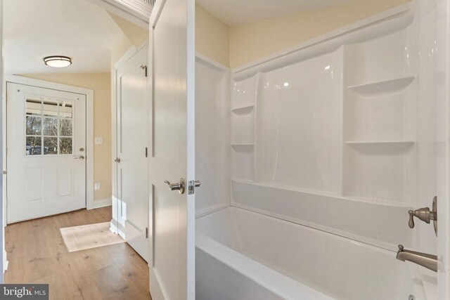 bathroom featuring washtub / shower combination and wood-type flooring