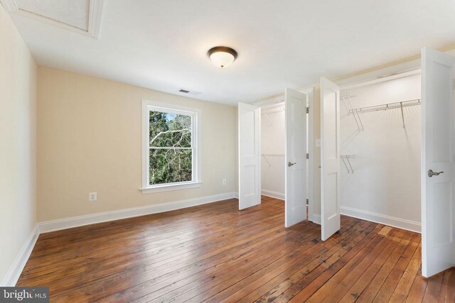 unfurnished bedroom with two closets and dark hardwood / wood-style flooring