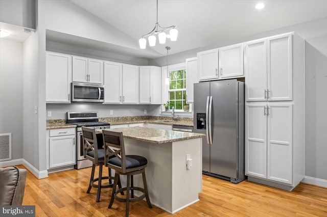 109 Poplar Dr, Louisa, VA 23093 - kitchen with stainless steel appliances, vaulted ceiling, light wood finished floors, light stone countertops, and a center island