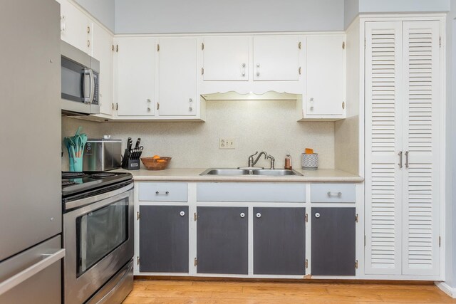 kitchen with light countertops, white cabinets, appliances with stainless steel finishes, and a sink