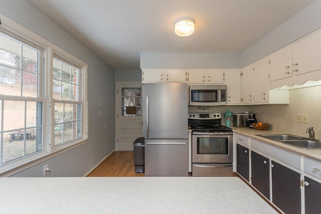 kitchen featuring white cabinets, light wood-style floors, appliances with stainless steel finishes, and a sink