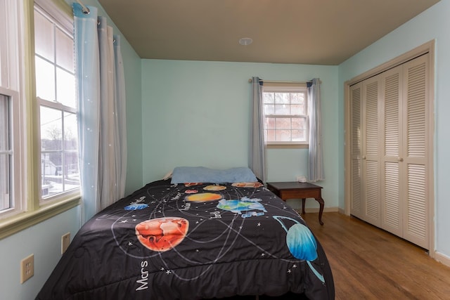bedroom with a closet, wood finished floors, and baseboards