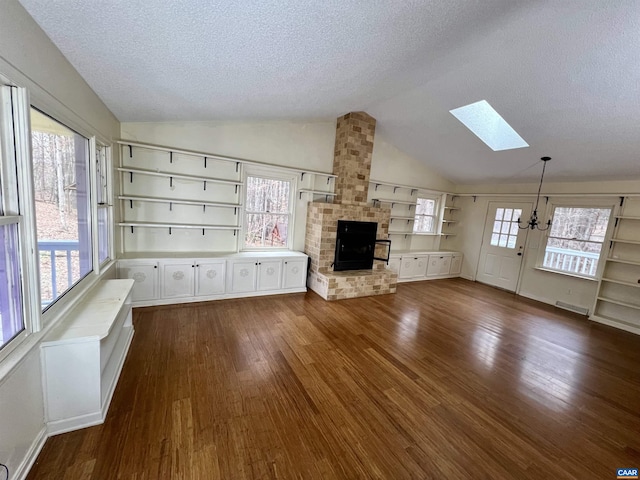 3264 Martin Kings Rd, Charlottesville, VA 22903 - unfurnished living room featuring a textured ceiling, lofted ceiling with skylight, a healthy amount of sunlight, dark wood finished floors, and a fireplace