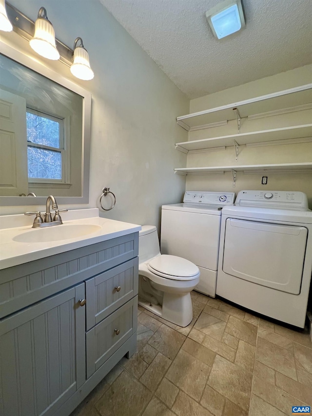 3264 Martin Kings Rd, Charlottesville, VA 22903 - bathroom with a textured ceiling, stone tile flooring, toilet, washer and dryer, and vanity