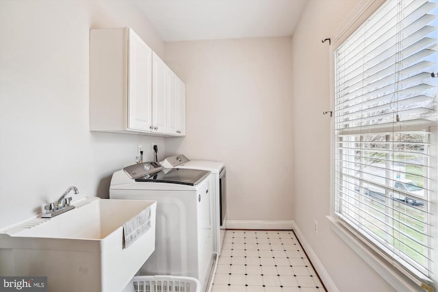 washroom featuring cabinet space, washing machine and clothes dryer, healthy amount of natural light, and baseboards