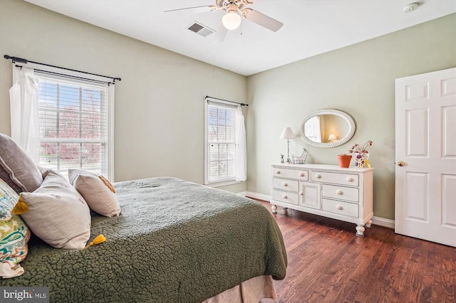 bedroom with multiple windows, wood finished floors, and baseboards