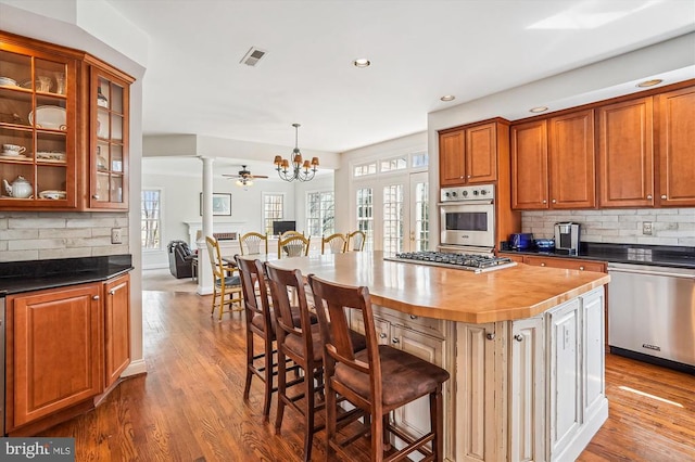 kitchen featuring stainless steel appliances, decorative backsplash, wood finished floors, and recessed lighting
