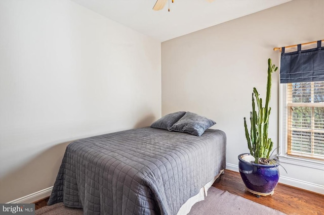 bedroom featuring baseboards, wood finished floors, and ceiling fan