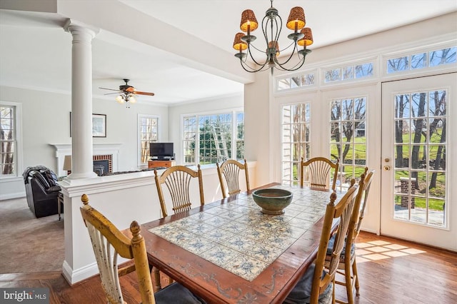 dining space featuring ornate columns, ceiling fan, a chandelier, crown molding, and baseboards