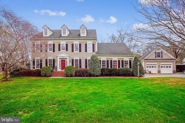colonial house with a detached garage, a front yard, and an outdoor structure