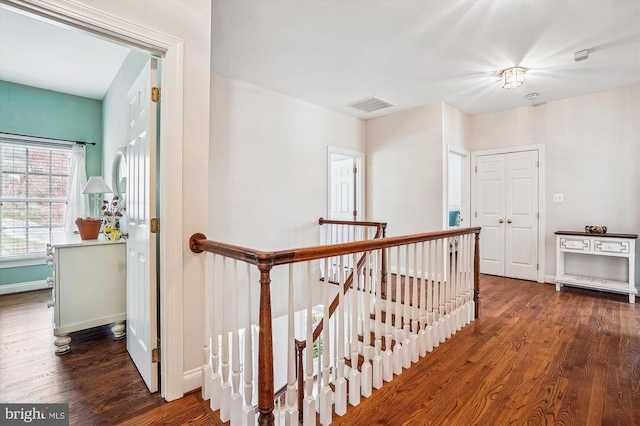 hall with an upstairs landing, wood finished floors, and baseboards
