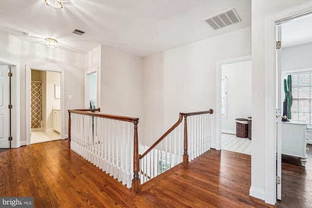 hallway with an upstairs landing, wood finished floors, and baseboards
