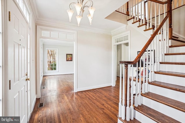 entrance foyer featuring a chandelier, ornamental molding, baseboards, wood finished floors, and stairway