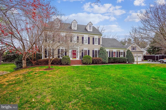 colonial house with a front yard, asphalt driveway, and a garage