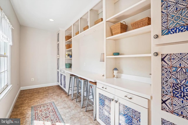 kitchen featuring open shelves, baseboards, and light countertops